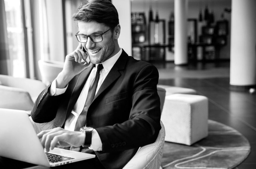 man on a laptop with a phone on the ear