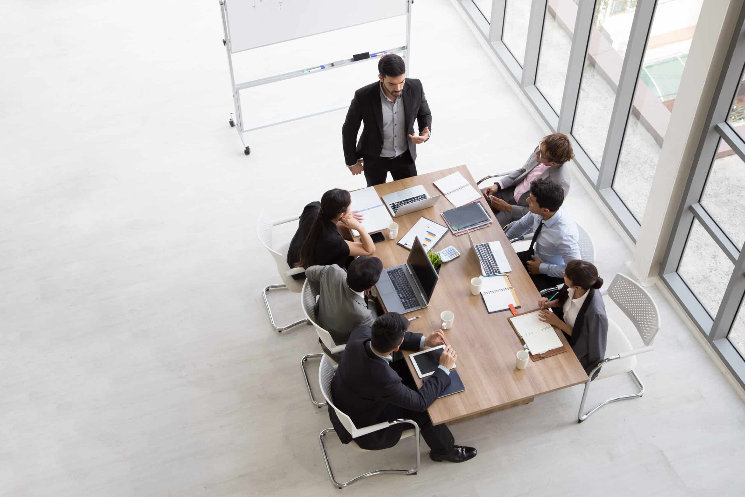 Top view of group of multiethnic busy people working in an office, Aerial view with businessman and businesswoman sitting around a conference table with blank copy space, Business meeting concept Top view of group of multiethnic busy people working in an office, Aerial view with businessman and businesswoman sitting around a conference table with blank copy space, Business meeting concept