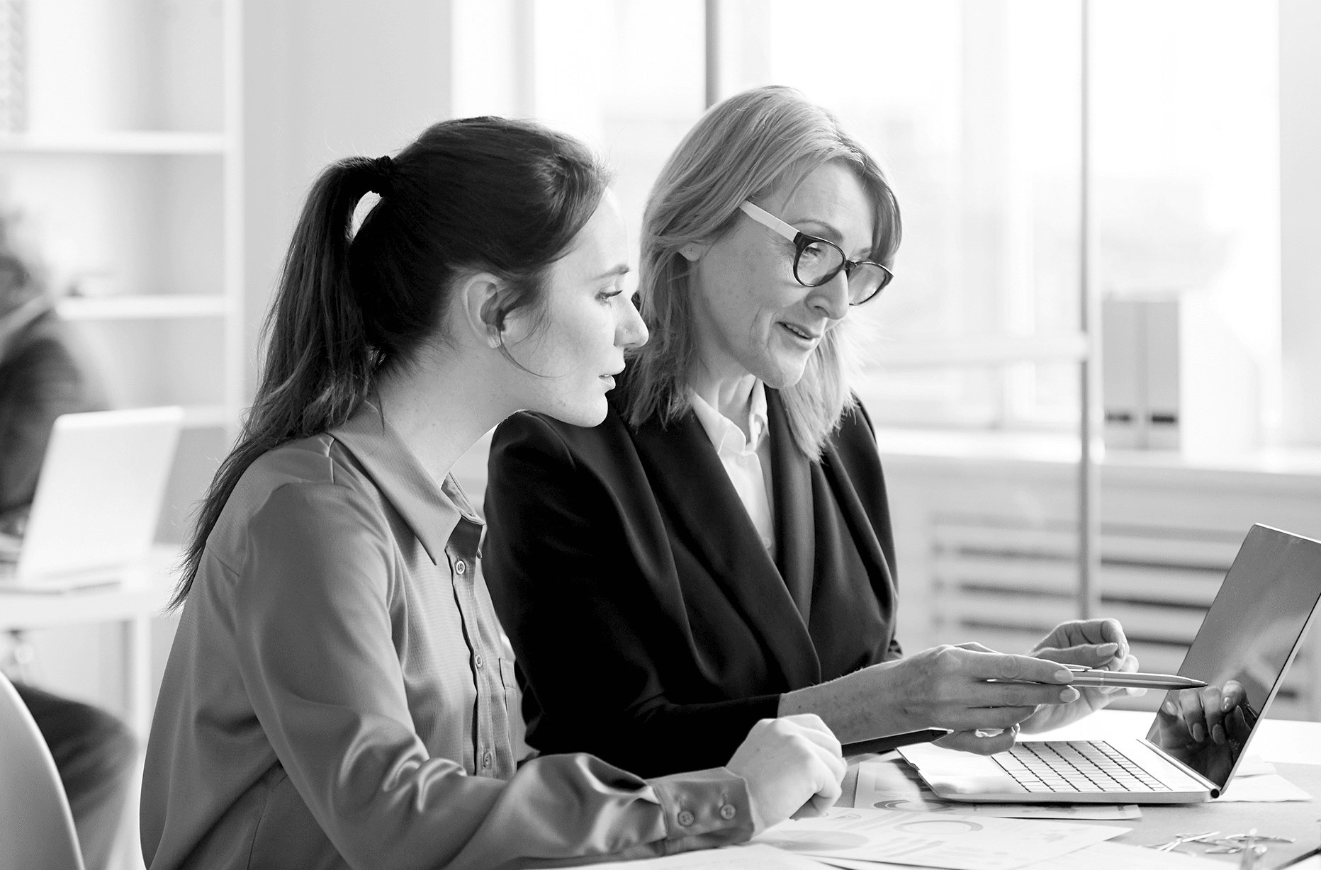 two woman discussing in front of a laptop