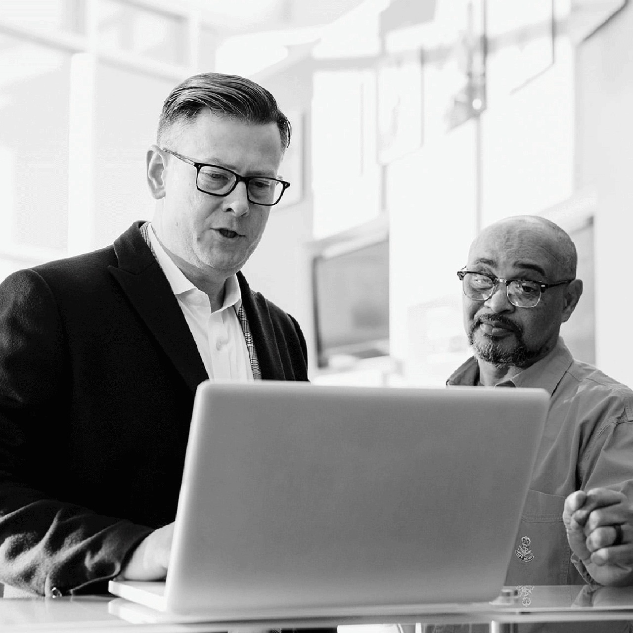 two men in front of a laptop
